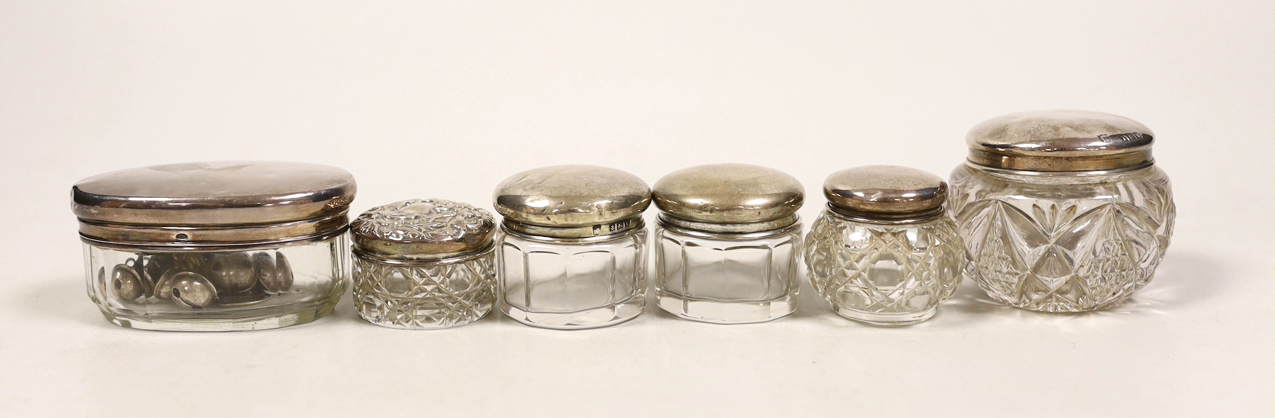 Six assorted small silver mounted glass toilet jars.